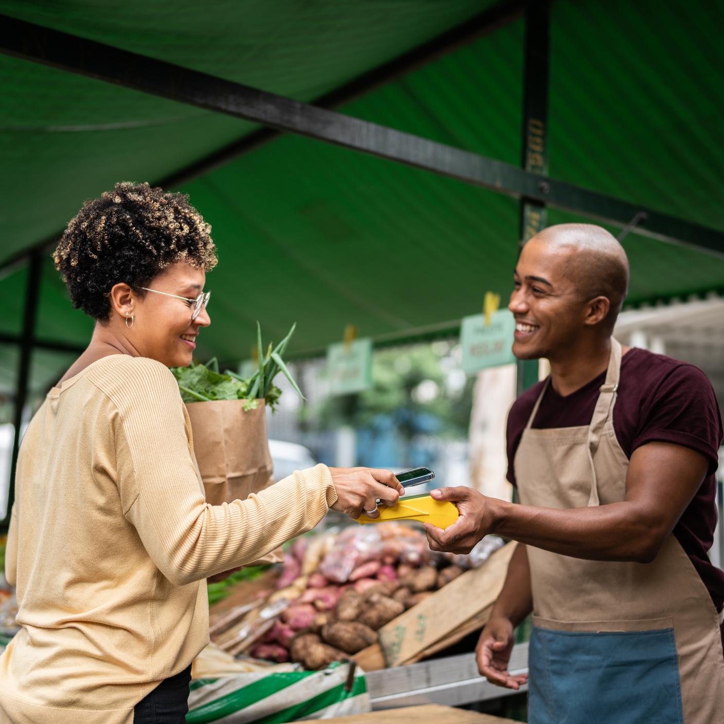 ICT - 年轻妇女在街头市场用手机付款