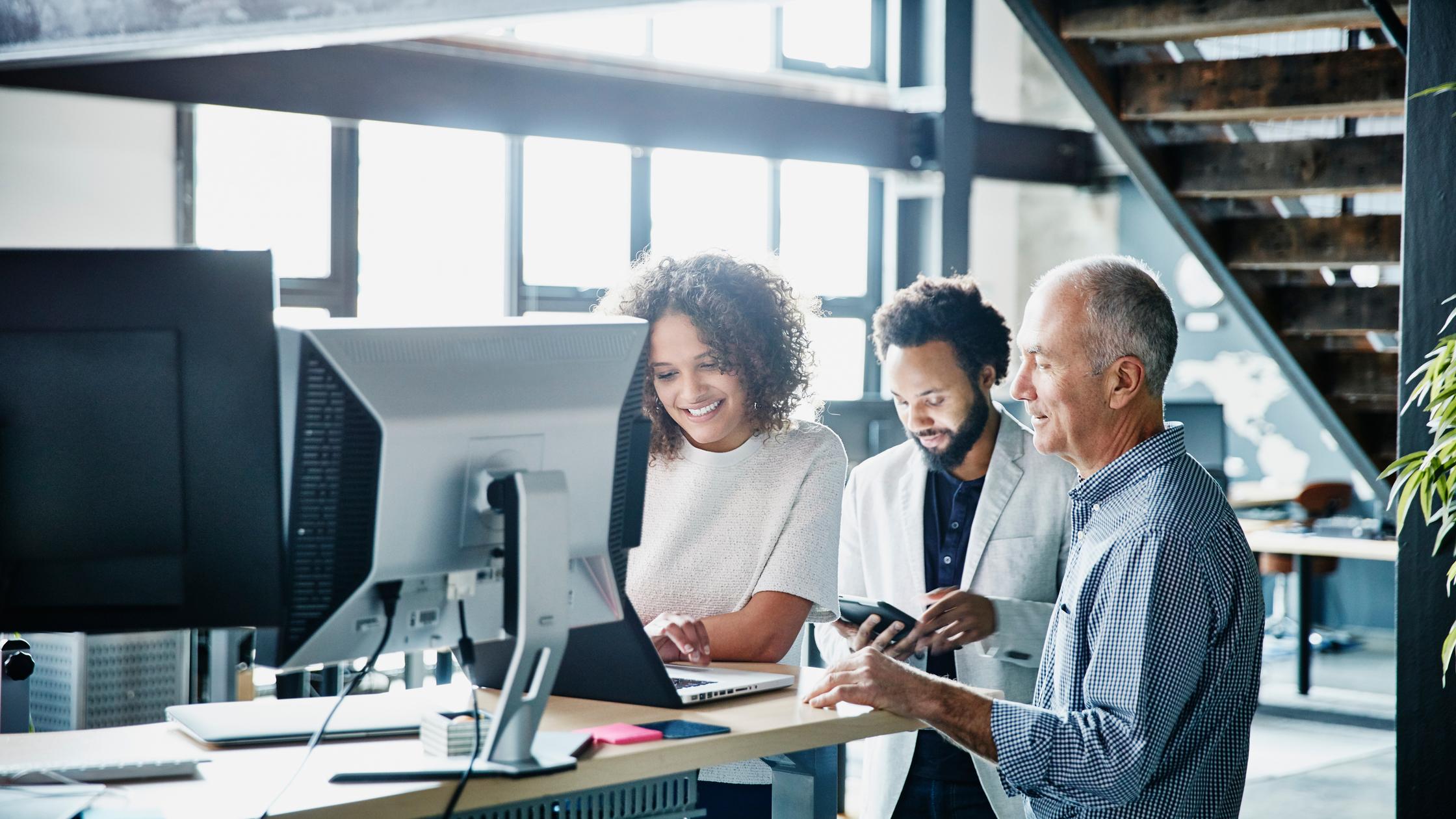 同事们在高科技办公室用笔记本电脑讨论项目