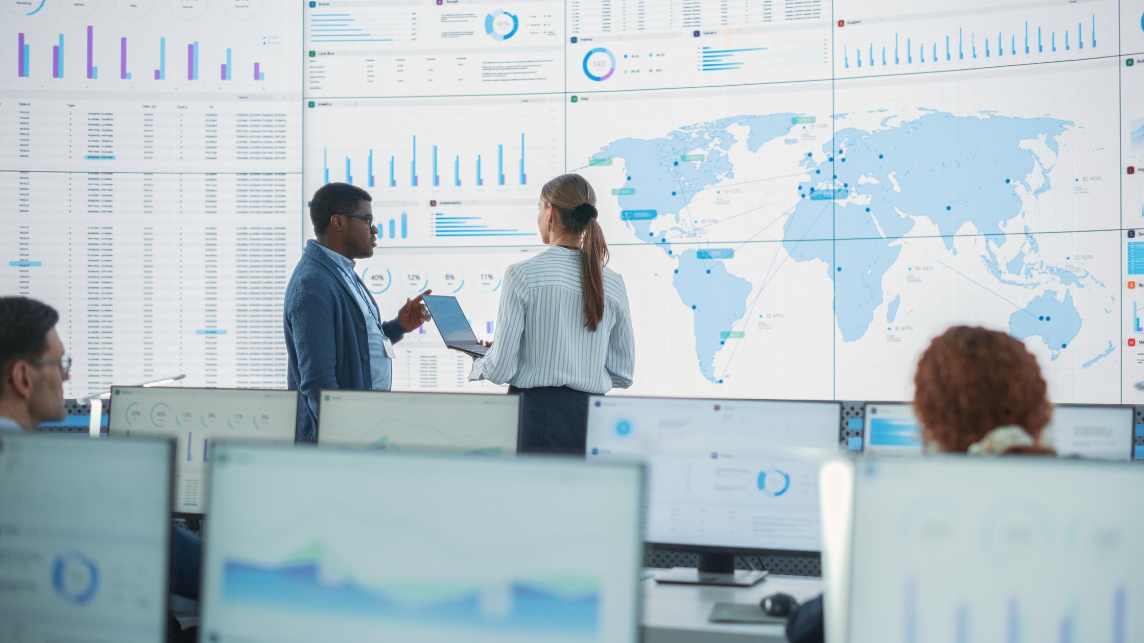 在台式电脑前工作的员工和讨论分析的同事