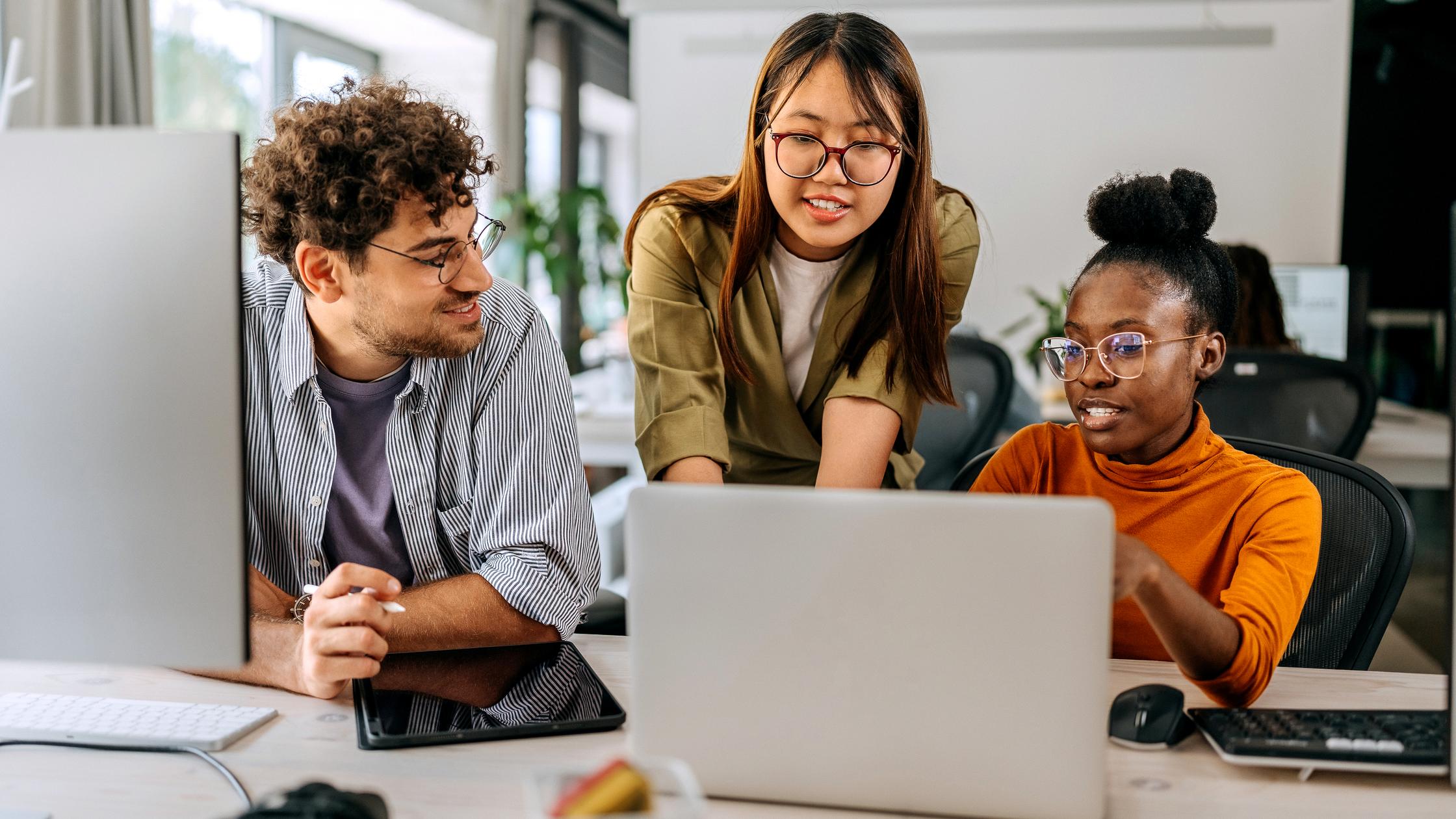 三个同事围在一台笔记本电脑旁